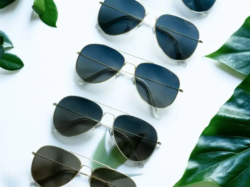 Four pairs of aviator sunglasses with dark lenses on a white surface