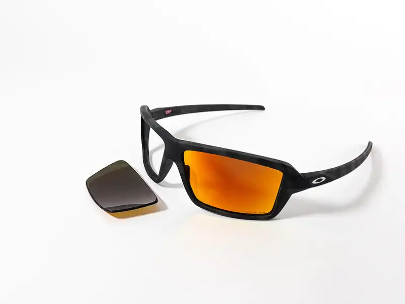 Oakley-Sportsonnenbrille mit orange verspiegelten Gläsern, daneben ein Ersatzglas.