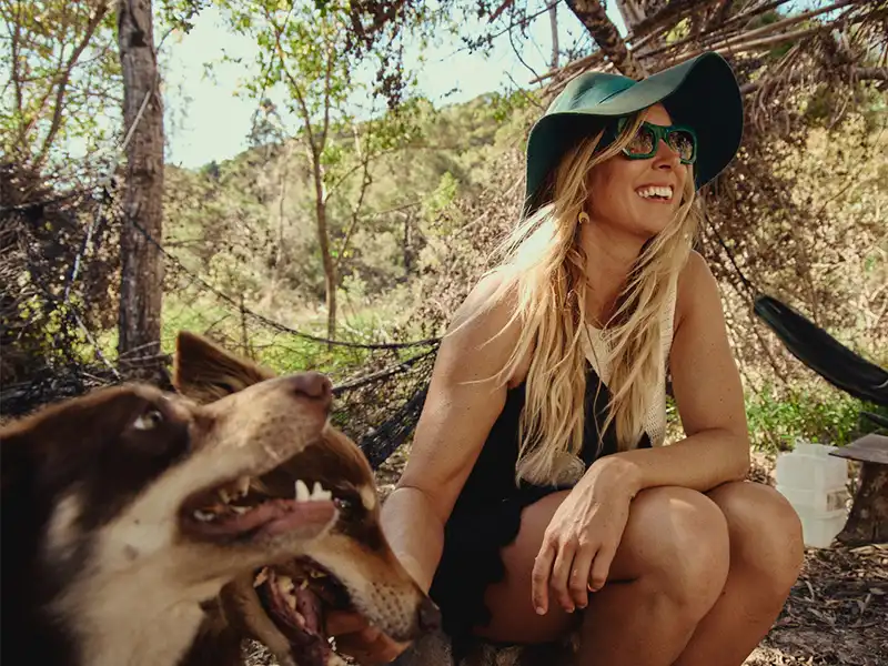 Lauren Hill lächelt mit ihrer Childe-Sonnenbrille und Hund Luna – ein Hinweis auf das Childe for Life Gläserersatzprogramm von The Sunglass Fix.