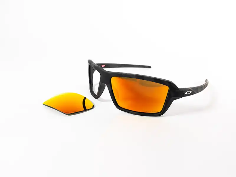Ein Paar Oakley-Sonnenbrillen mit sauberen, orange gespiegelt Gläsern, von denen eines entfernt wurde