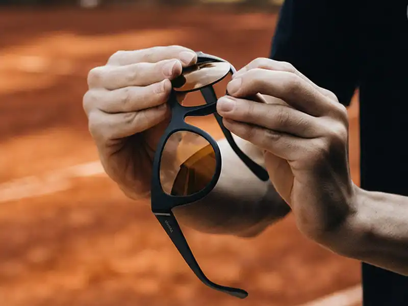 Hände beim Austausch von Sonnenbrillengläsern zur Verbesserung der Sicht für die Tennis-Performance