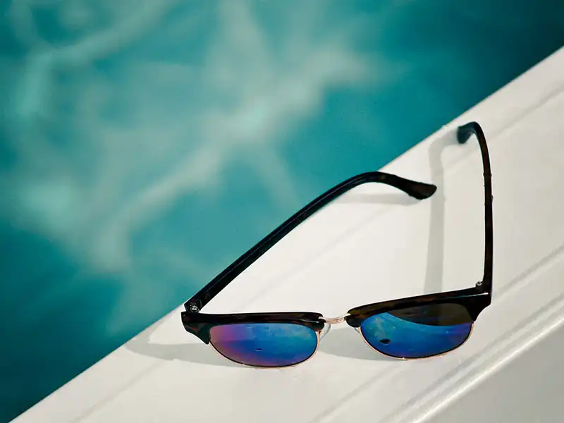 Polarisierte Sonnenbrille mit verspiegelten Gläsern neben einem Schwimmbecken