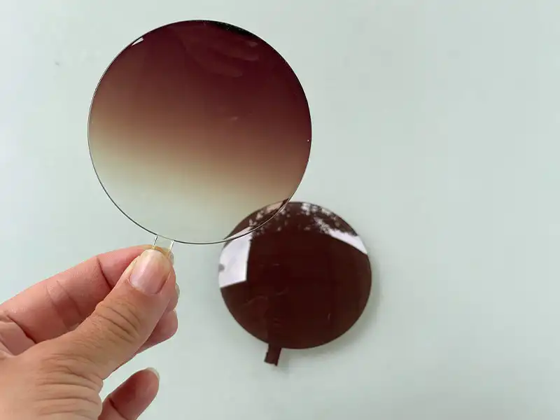 Hand holding sunglasses lens uncut to check optical clarity Hand holding sunglasses lens uncut to check optical clarity
