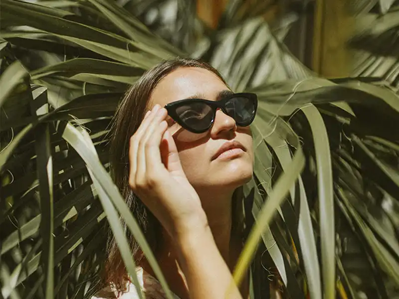 Persona con gafas de sol negras estilo cat-eye, mostrando cómo protegen los ojos con protección UV del sol.