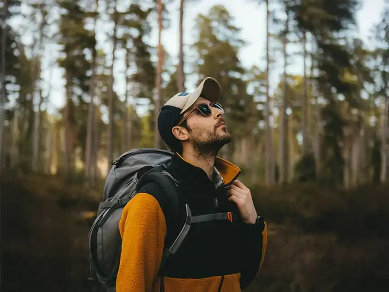 Caminante con gafas de sol polarizadas con un paisaje forestal al fondo