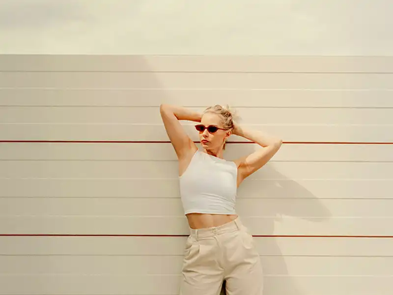 Mujer con gafas de sol delgadas y rectangulares diseñadas con una estética minimalista de los años 90, una de las tendencias clave en gafas para 2025.