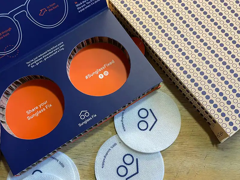 Top shot of The Sunglass Fix recyclable packaging, with the blue and orange box, the lens holder and shipping box. Top shot of The Sunglass Fix recyclable packaging, with the blue and orange box, the lens holder and shipping box.