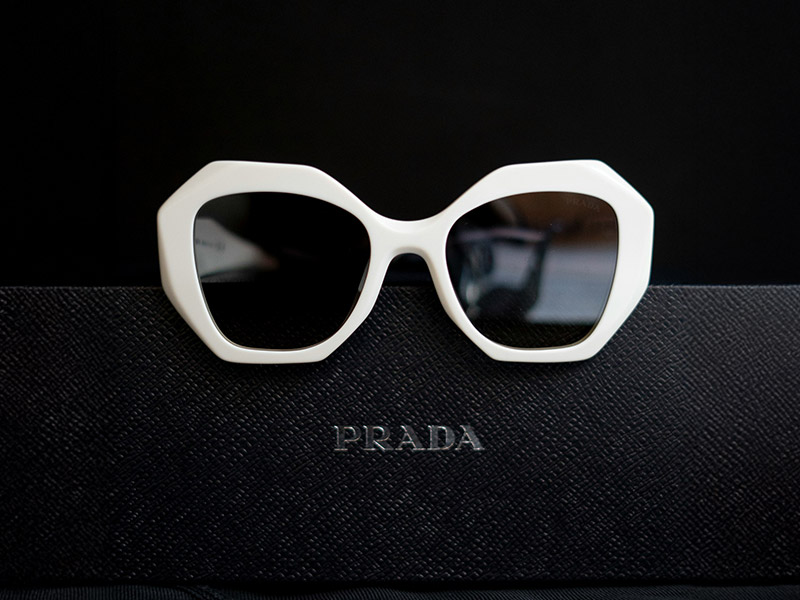 White geometric sunglasses by Prada, representing the bold and futuristic shield trend for 2025.