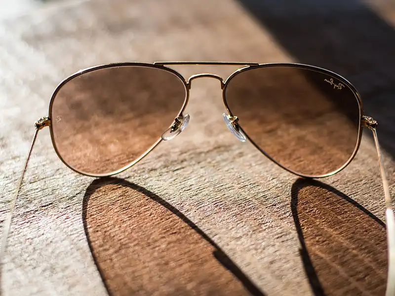 Gros plan sur des lunettes de soleil aviateur avec des verres teintés marron, une couleur de verre efficace et apaisante pour gérer la photophobie et la sensibilité à la lumière.