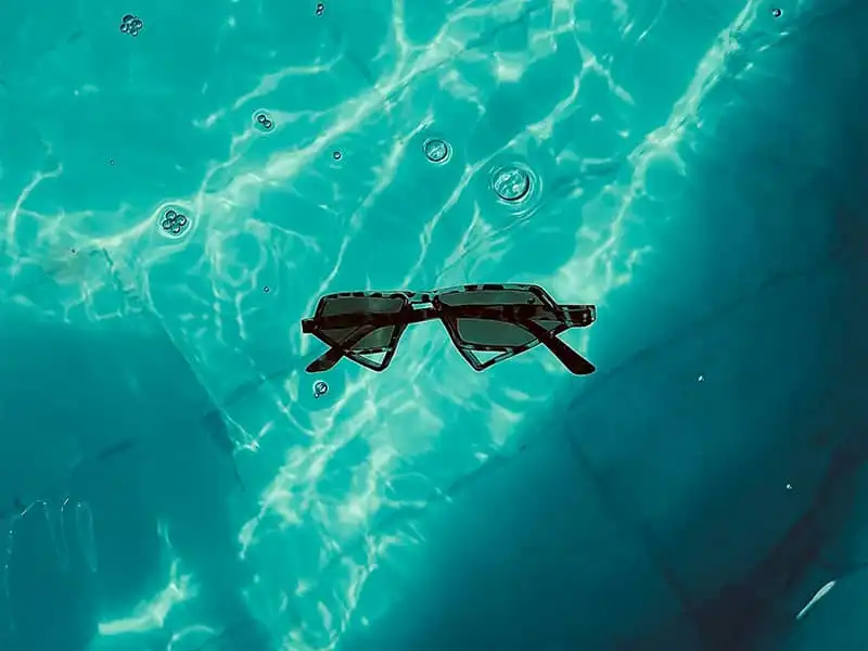Floating rectangular shaped sunglasses in turquoise pool water