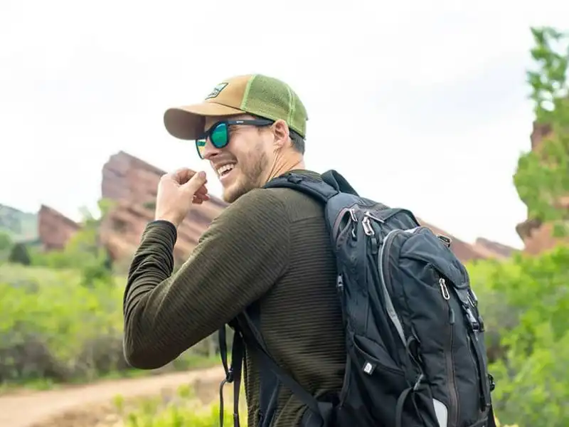 Man with sunglasses smiling while hiking on a picturesque mountain path