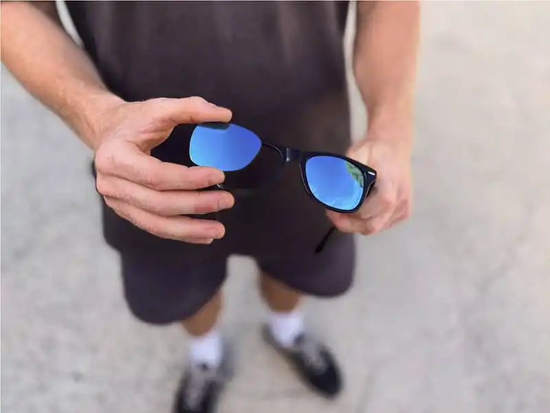 Close-up of a person replacing the lenses in a pair of black sunglasses