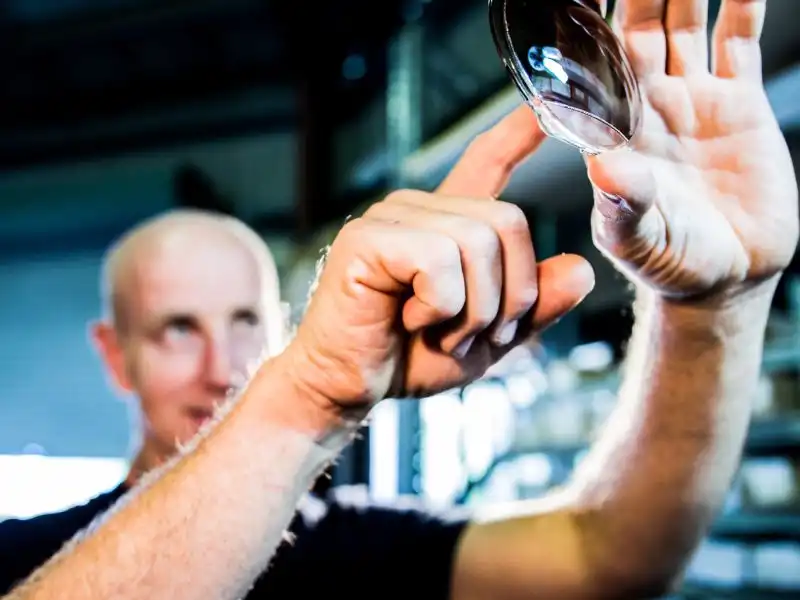 Craig Anderson, founder and CEO of The Sunglass Fix, inspecting a sunglass lens inside the workshop.