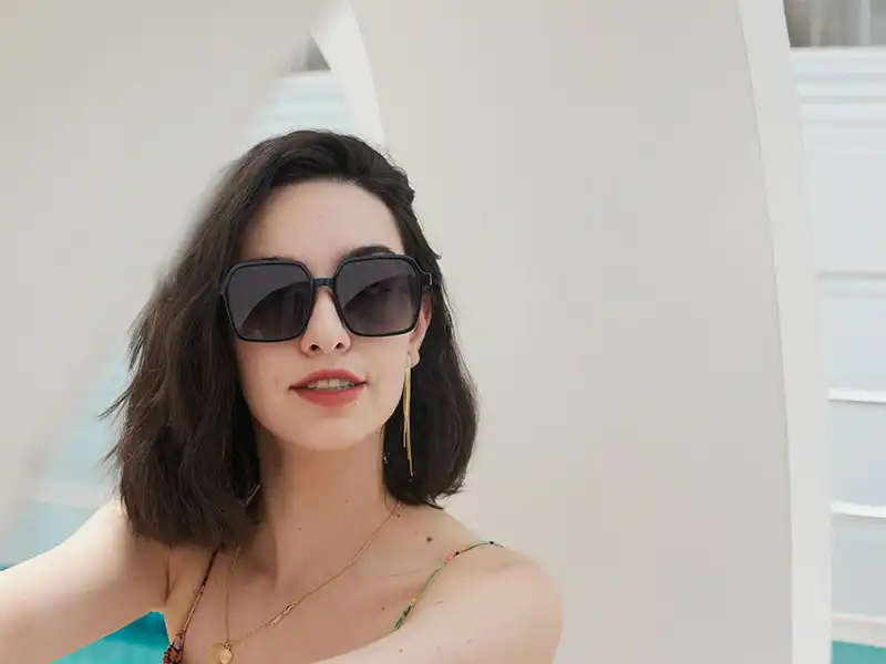 Mujer con gafas de sol de gran tamaño con montura cuadrada, que reflejan la audaz tendencia de glamour para las gafas de moda de 2025.