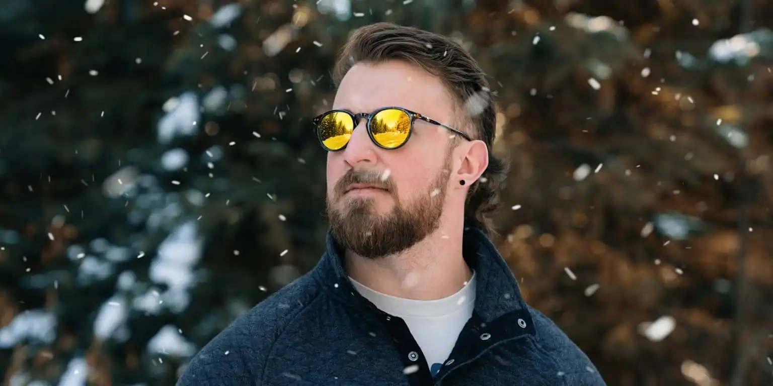 Man in the snow wearing circular gold reflective glasses