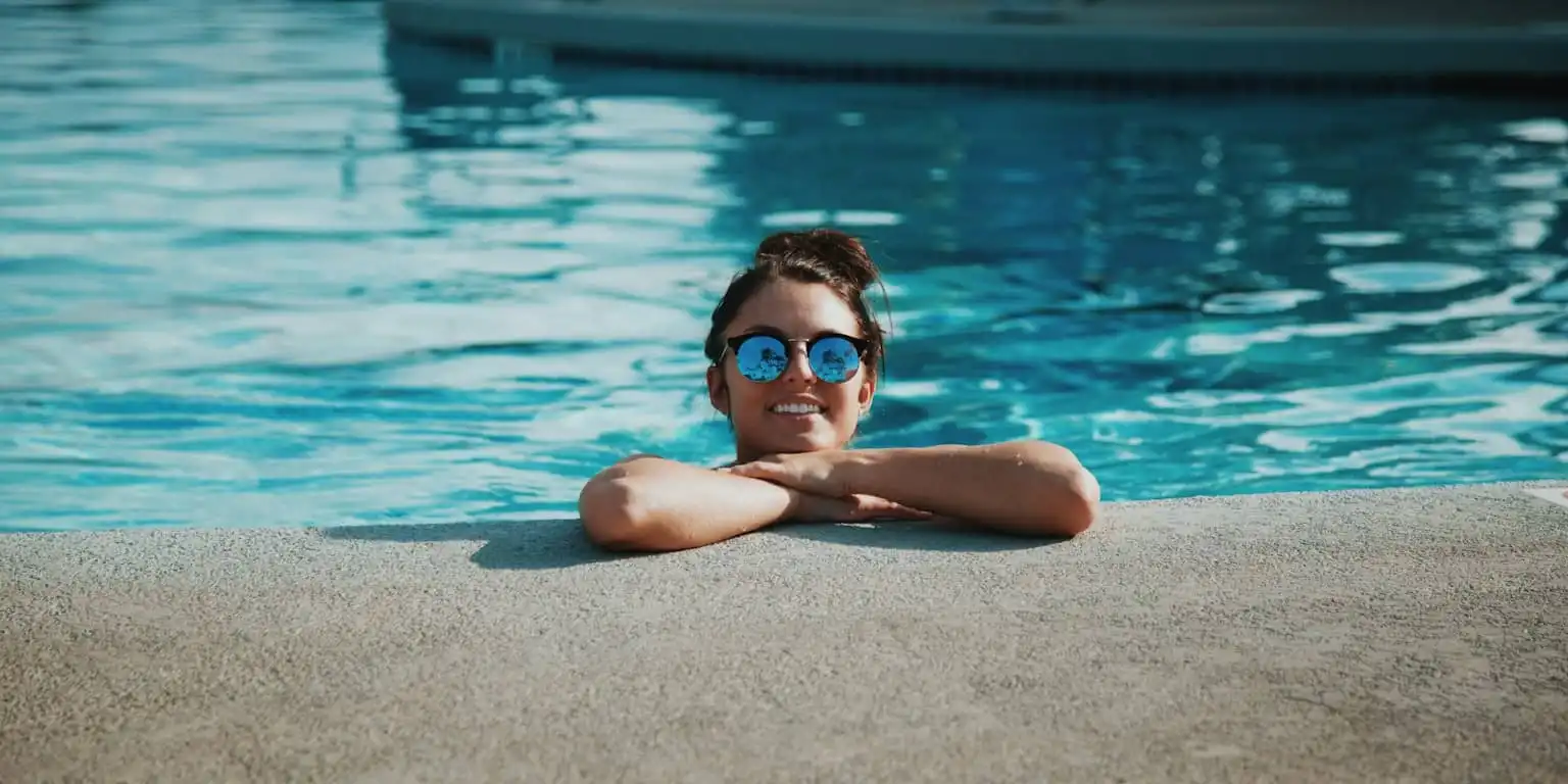 Girl in a pool with blue reflective sunglasses on