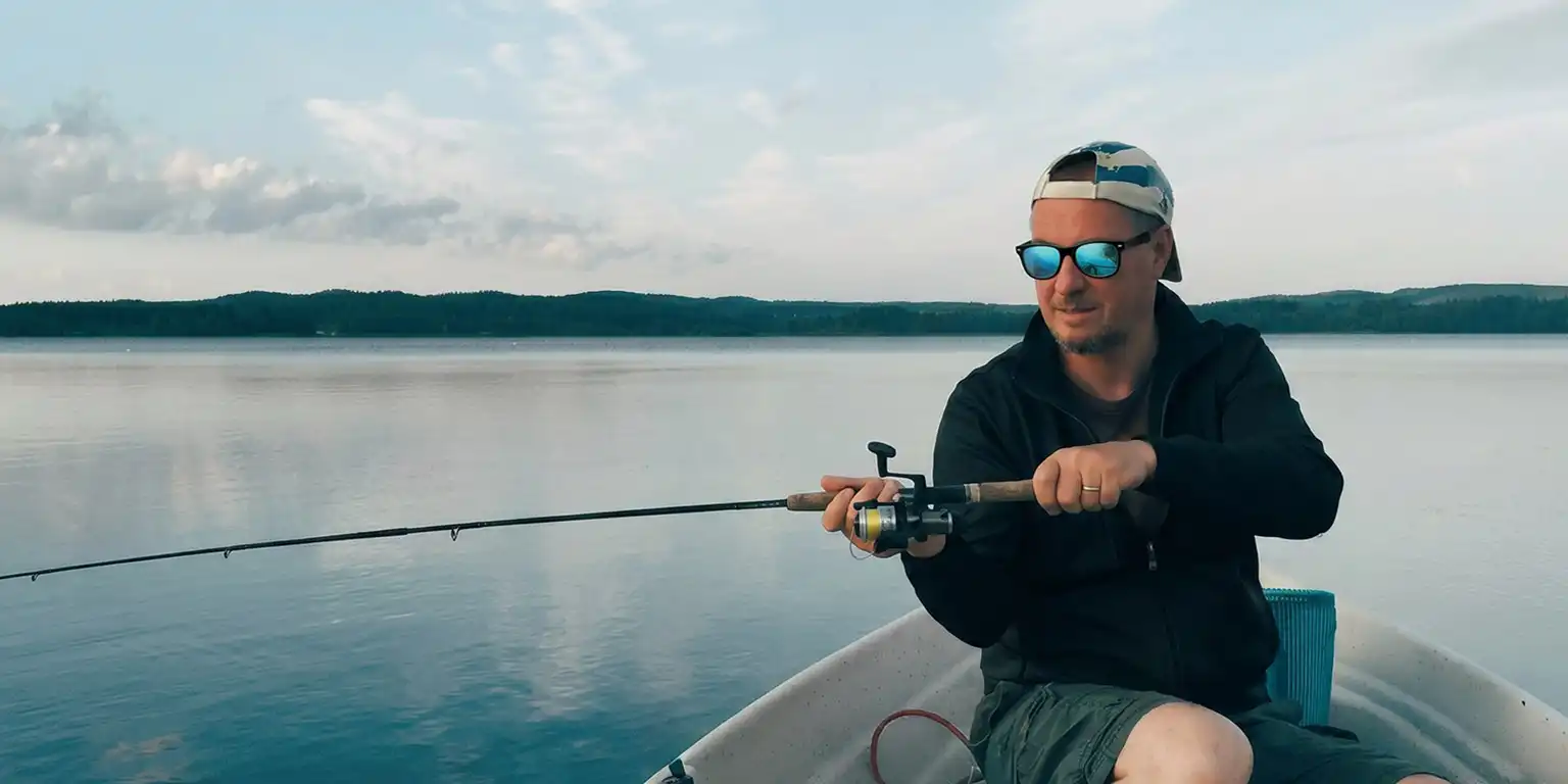 Man on boat in a lake casting a fishing rod